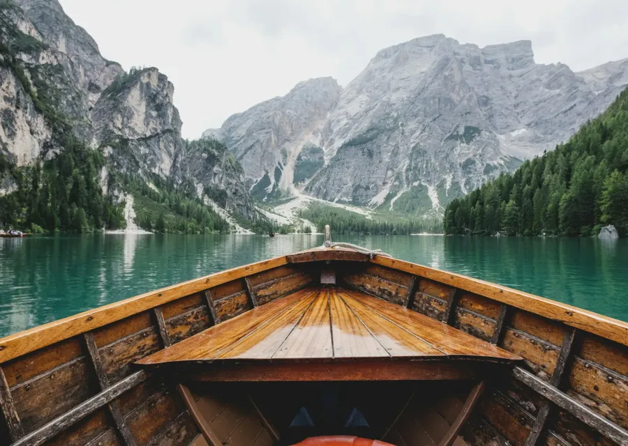 Wooden rowboat on an emerald alpine lake below grey peaks