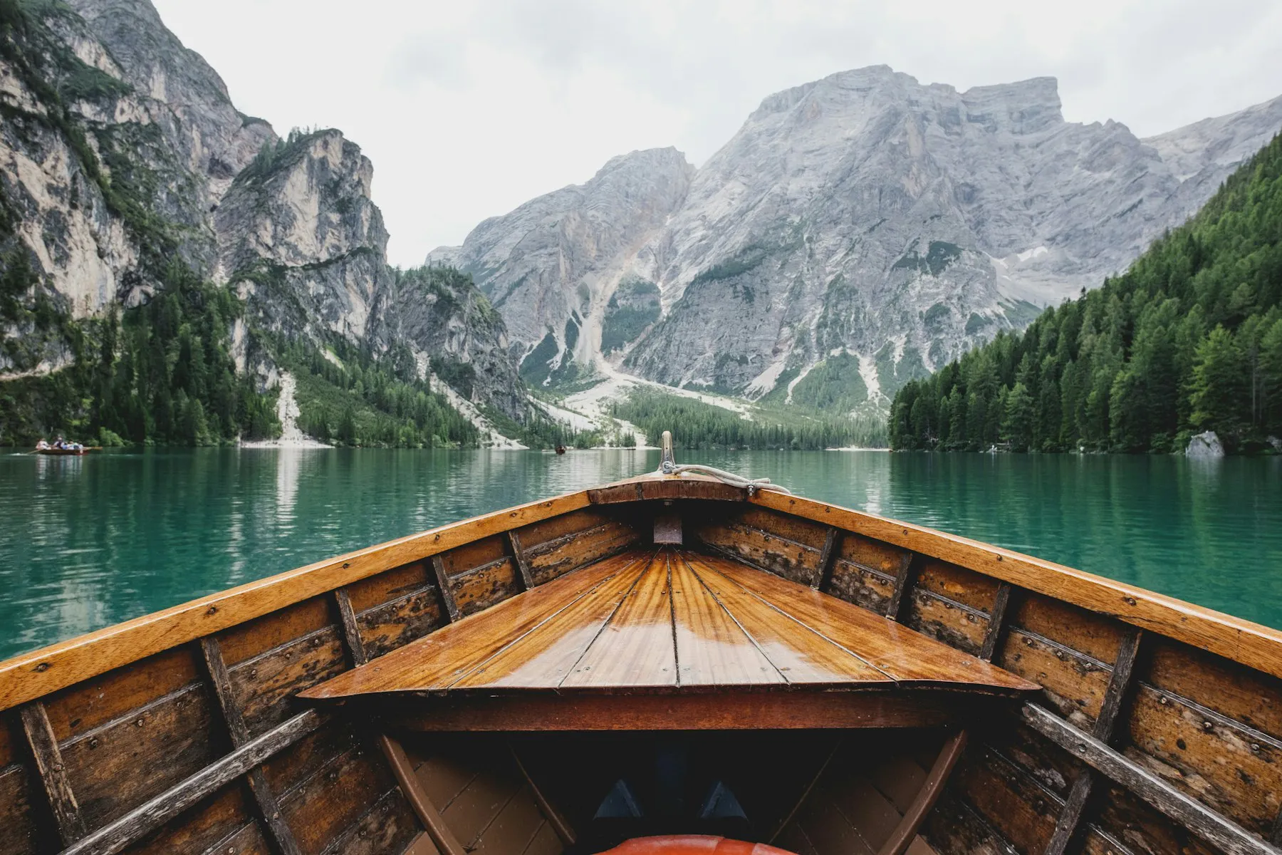 Wooden rowboat on an emerald alpine lake below grey peaks