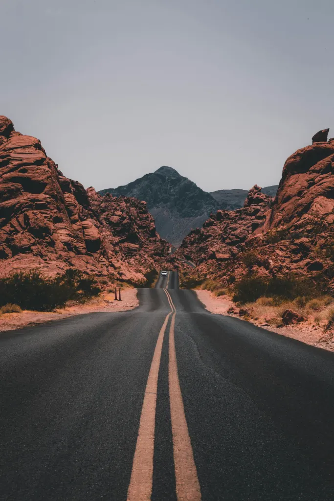 Straight two-lane highway leading toward red desert buttes