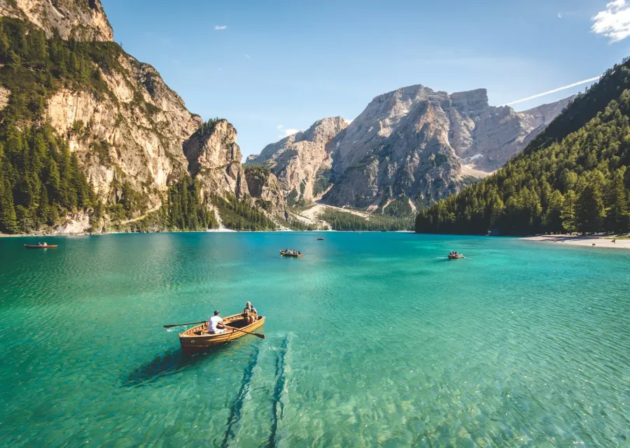 Small boat with two people on a turquoise lake between mountains