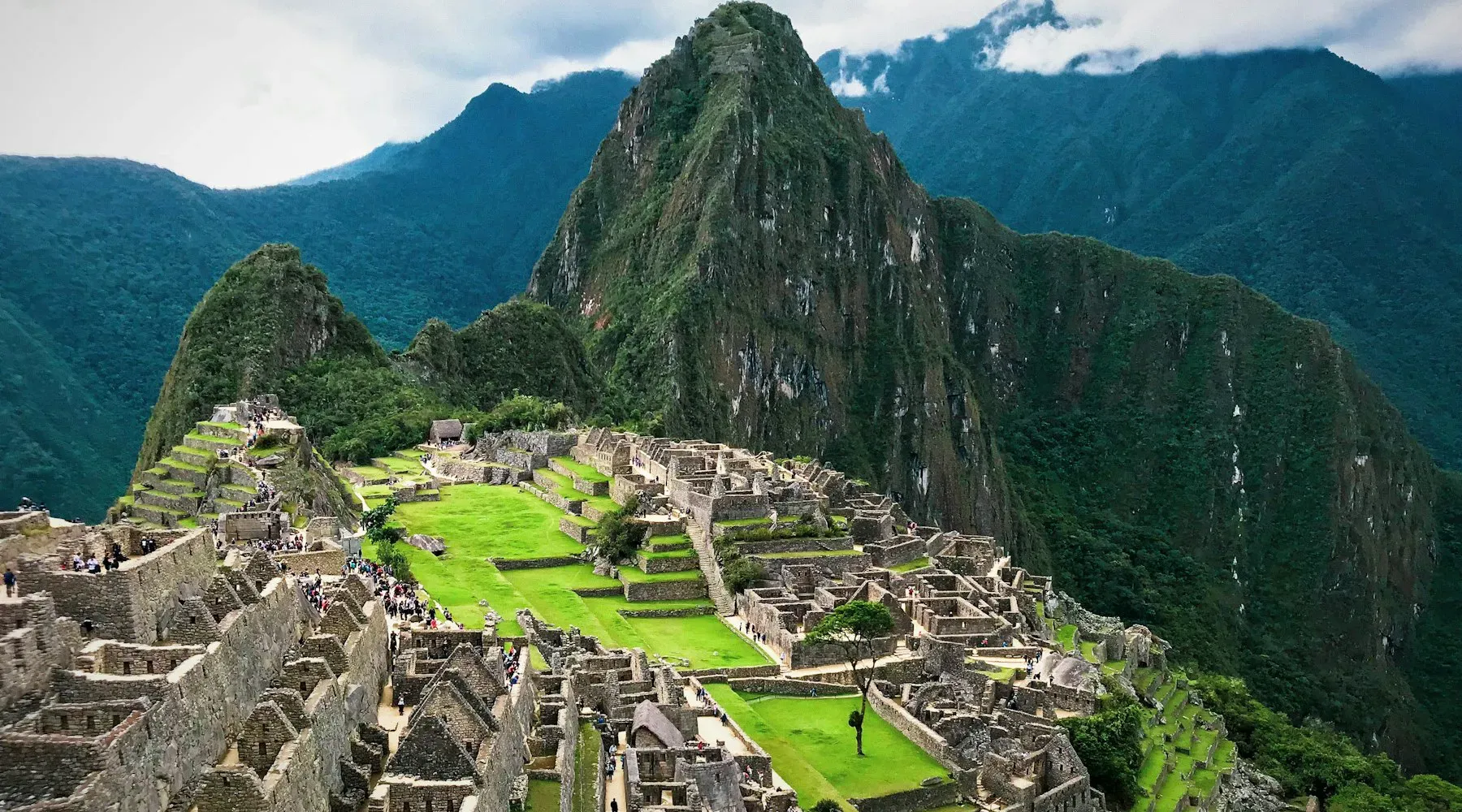 Machu Picchu terraces below green peaks