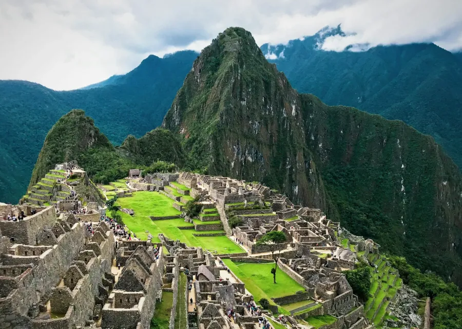 Machu Picchu terraces below green peaks